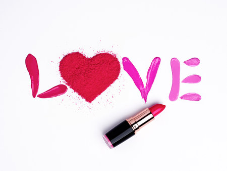 Valentine's Day background. Red and pink lipstick smeared in the shape of the letters love. Isolated on white background. Cosmetic products. Beauty and makeup conceptの写真素材