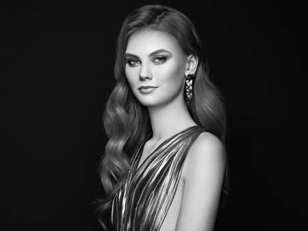 Brunette girl with perfect makeup. Beautiful model woman with curly hairstyle. Care and beauty hair products. Lady with fashionable makeup. Model with jewelry on dark backgroundの写真素材