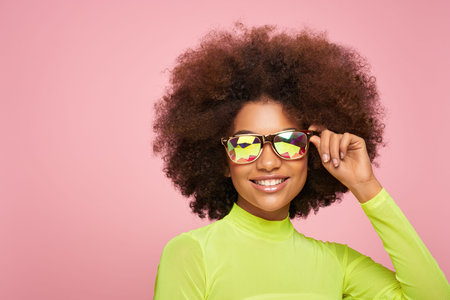 Beauty portrait of African American girl in colored holographic sunglasses. Beautiful black woman on...