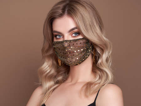 Blonde woman with luxury designer protective face mask.Trendy Fashion accessory during quarantine of coronavirus pandemicの写真素材