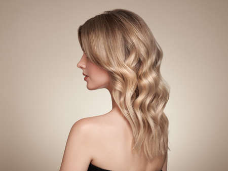 Blonde woman with long and shiny curly hair. Beautiful model girl with curly hairstyle. Care and beauty hair productsの写真素材