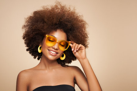 Beauty portrait of African American girl in colored sunglasses. Beautiful black woman. Cosmetics, makeup and fashionの写真素材