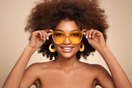 Beauty portrait of African American girl in colored sunglasses. Beautiful black woman. Cosmetics, makeup and fashionの写真素材