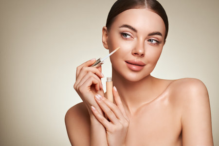 Portrait beautiful young woman with clean fresh skin. Model with foundation makeup bottle. Cosmetology, beauty and spaの写真素材