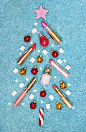 Christmas tree made from winter decorations and cosmetic products on blue background. Holiday and celebration creative concept. Flat lay, top viewの写真素材
