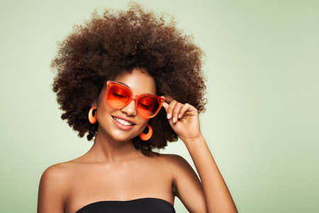 Beauty portrait of African American girl in colored sunglasses. Beautiful black woman. Cosmetics, makeup and fashionの写真素材