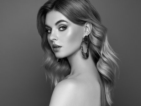 A beautiful young woman with shiny wavy blonde hair. Model with healthy skin, close up portrait. Cosmetology, beauty and spaの写真素材