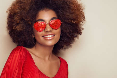 Beautiful portrait of an African girl in sunglasses in the shape of hearts. Valentine's Day. Symbol of loveの写真素材