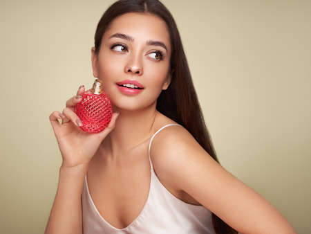 Young beautiful woman with a bottle of perfume. Model with healthy skin, close up portrait. Cosmetology, beauty and spaの写真素材