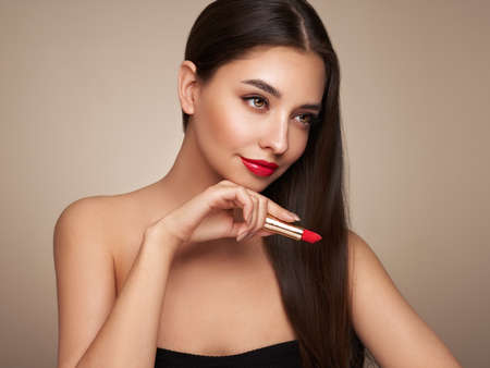 A beautiful young woman applying lipstick. Model with healthy skin, close up portrait. Cosmetology, beauty and spaの写真素材