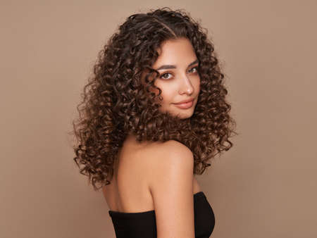 Fashion studio portrait of beautiful smiling woman with afro curls hairstyle. Fashion and beautyの写真素材