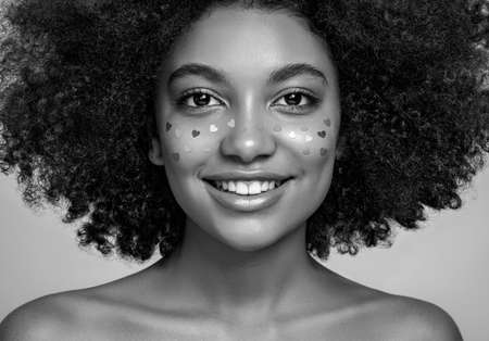 Beauty portrait of African American girl with afro hair. Beautiful black woman. A Womans face decorated with decorative hearts. Valentines day photoの写真素材