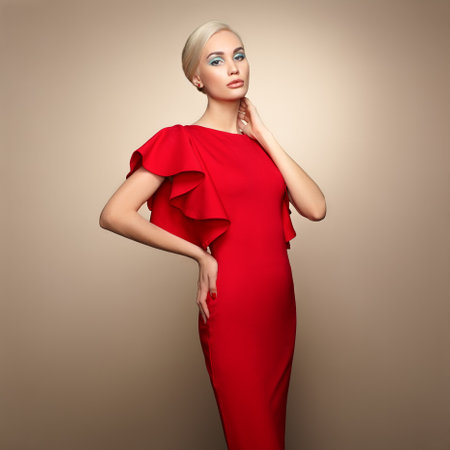 Fashion portrait of elegant woman with magnificent hair. Blonde girl. Perfect make-up. Girl in elegant red dress. Girl posing. Studio photoの写真素材