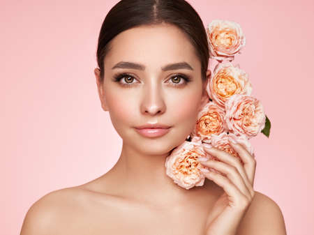 Portrait beautiful young woman with clean fresh skin. Model with healthy skin, close up portrait. Cosmetology, beauty and spa. Girl with a rose flowerの写真素材