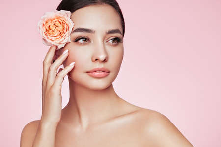 Portrait beautiful young woman with clean fresh skin. Model with healthy skin, close up portrait. Cosmetology, beauty and spa. Girl with a rose flowerの写真素材
