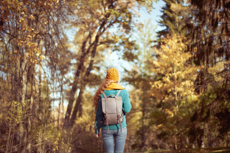 A young red-haired woman walks through the autumn park. A girl with lush curly hair looks at the autumn forestの写真素材
