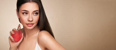 Young beautiful woman with a bottle of perfume. Model with healthy skin, close up portrait. Cosmetology, beauty and spaの写真素材