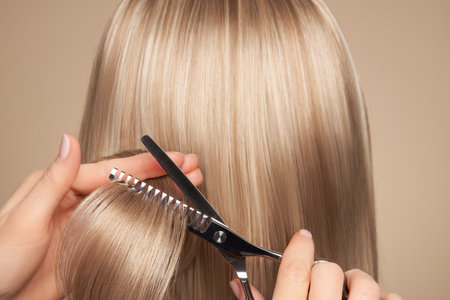 Hairdresser cuts long blonde hair with scissors. Hair salon, hairstylist. Care and beauty hair products. Dyed hairの写真素材