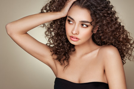Fashion studio portrait of beautiful woman with afro curls hairstyle. Facial treatment. Cosmetology, beauty and spaの写真素材