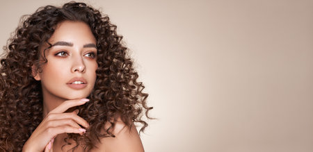 Fashion studio portrait of beautiful woman with afro curls hairstyle. Facial treatment. Cosmetology, beauty and spaの写真素材