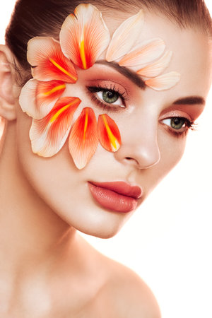Portrait of beautiful young woman with makeup petals. Brunette woman with luxury makeup. Perfect skin. Eyelashes. Cosmetic eyeshadowの写真素材