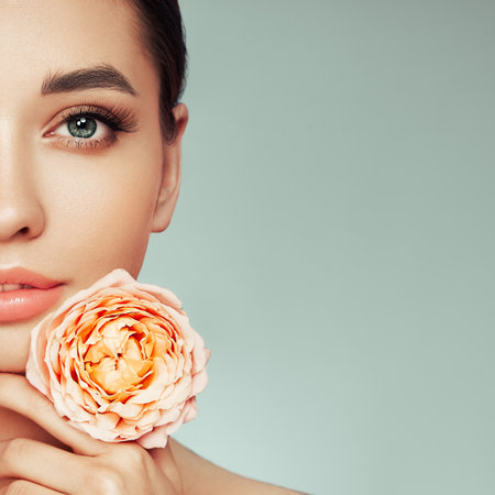 Portrait beautiful young woman with clean fresh skin. Model with healthy skin, close up portrait. Cosmetology, beauty and spa. Girl with a rose flowerの写真素材