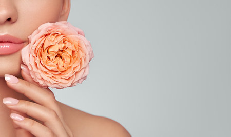 Portrait beautiful young woman with clean fresh skin. Model with healthy skin, close up portrait. Cosmetology, beauty and spa. Girl with a rose flowerの写真素材