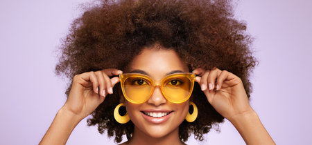 Beauty portrait of African American girl in colored sunglasses. Beautiful black woman. Cosmetics, makeup and fashionの写真素材