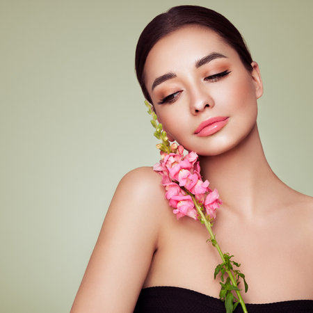 Portrait beautiful young woman with clean fresh skin. Model with healthy skin, close up portrait. Cosmetology, beauty and spa. Girl with a pink  flowerの写真素材