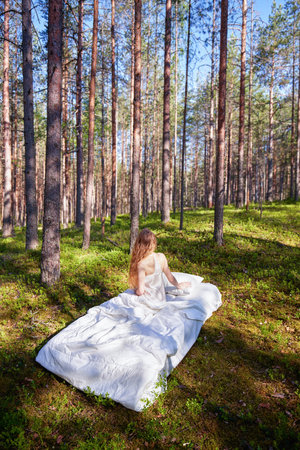 Woman sleeps on a mattress in the summer forest. The girl is resting in natureの写真素材