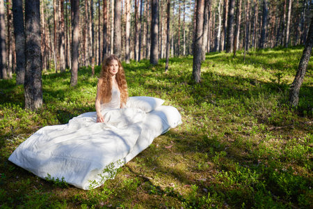 Woman sleeps on a mattress in the summer forest. The girl is resting in natureの写真素材