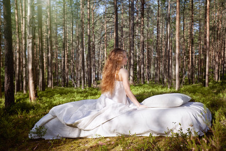 Woman sleeps on a mattress in the summer forest. The girl is resting in natureの写真素材