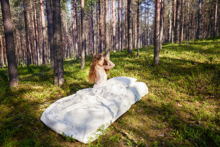 Woman sleeps on a mattress in the summer forest. The girl is resting in natureの写真素材