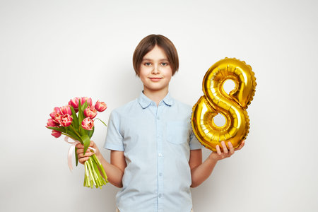 Cheerful happy child with Tulips bouquet and balloon number 8. Smiling boy on white background,...