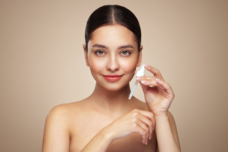 Young beautiful woman applying face serum with pipette. Cosmetic procedures for facial skin careの写真素材