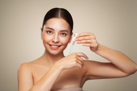 Young beautiful woman applying face serum with pipette. Cosmetic procedures for facial skin careの写真素材