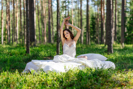 Woman sleeps on a mattress in the summer forest. Girl wakes up in a summer forestの写真素材