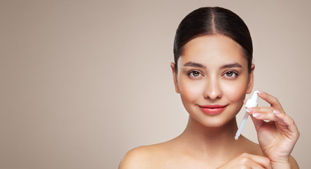 Young beautiful woman applying face serum with pipette. Cosmetic procedures for facial skin careの写真素材