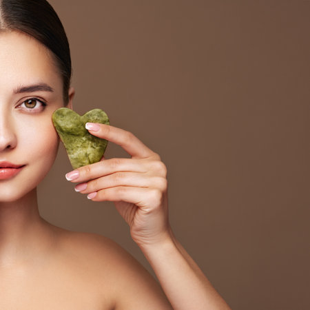 Beauty young woman doing skin care routine, scrapping, massage facial skin with jade gua sha scrapper, Facial treatment for anti aging and cosmetic cleaningの写真素材