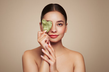 Beauty young woman doing skin care routine, scrapping, massage facial skin with jade gua sha scrapper, Facial treatment for anti aging and cosmetic cleaningの写真素材