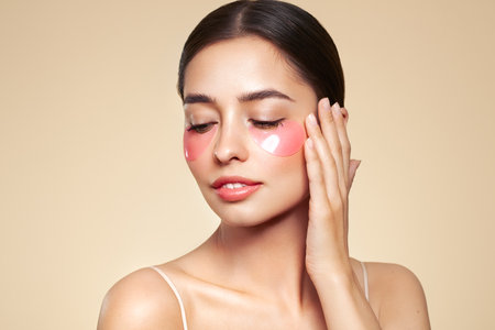 A young beautiful smiling woman with cosmetic patches on her eyes. Cosmetic procedures skin care around the eyes. Perfect healthy facial skinの写真素材