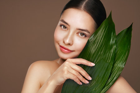 Close up girl face with green exotic leaves. Skin care beauty treatments concept. Model with clean, health skin of faceの写真素材
