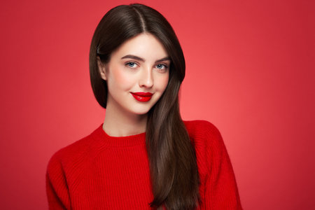 Portrait beautiful young woman with clean fresh skin. Model in red cardigan close up portrait. Cosmetology, beauty and spaの写真素材