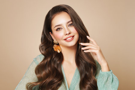 Brunette girl with perfect makeup. Smiling beautiful model woman with long curly hairstyle. Care and beauty hair productsの写真素材