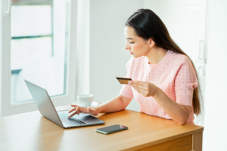 Young attractive woman shopping online with a laptop computer using a credit card. e-commerce, business concept. Freelance, remote workの写真素材