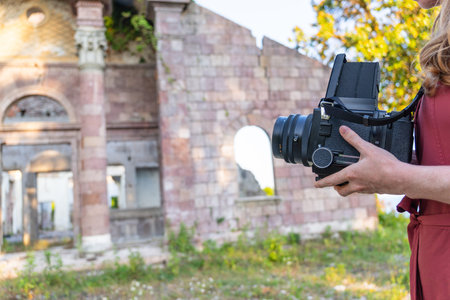 A beautiful young stylish woman photographs antique architecture with a retro film camera, Holiday...