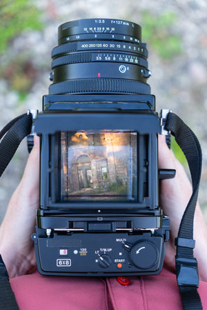 A woman looks through the viewfinder of a vintage medium format camera. In the viewfinder, she sees...
