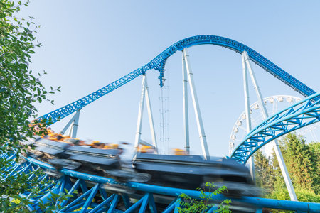 Roller coaster Ride against blue sky. Roller coaster in the amusement park. Cheerful entertainments in park of attractionsの写真素材