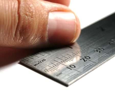 Ruler  An image of a hand in the act of measuring with a metal ruler, white backgroundの写真素材