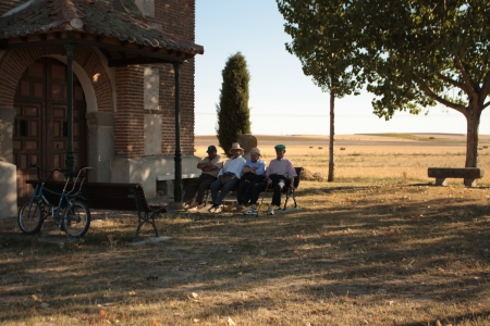 Marugan, Castilla y Leon, Spain  July 24, 2010  Four elderly men sitting lazily on a bench beside a church at noon, in the background Spanish dry fieldsのeditorial素材